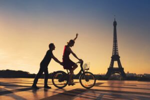 Couple sur un vélo devant la tour Eiffel au coucher du soleil