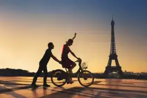 Couple sur un vélo devant la tour Eiffel au coucher du soleil