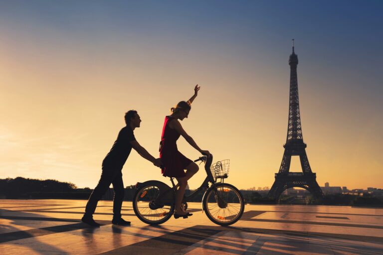 Couple sur un vélo devant la tour Eiffel au coucher du soleil