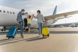 Parents et petite fille avec leur valise devant un avion pour un tour du monde