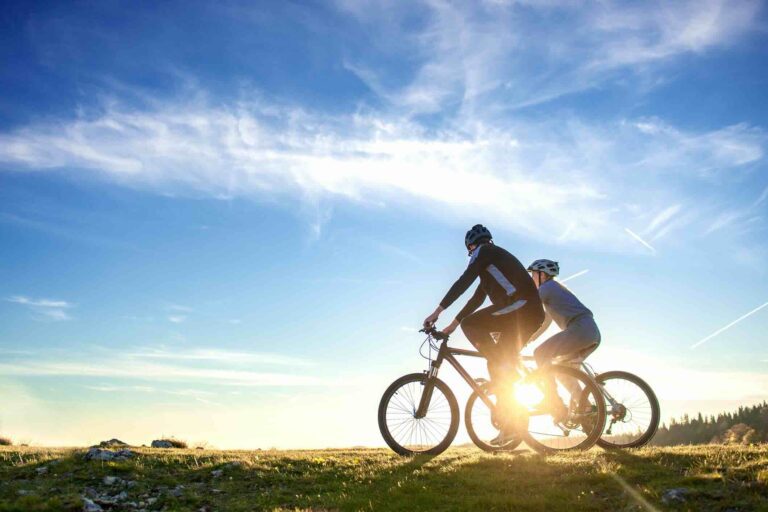Couple faisant du vélo dans la campagne avec le soleil en fond