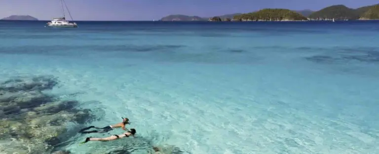 deux personnes en train de faire du snorkeling dans une eau turquoise