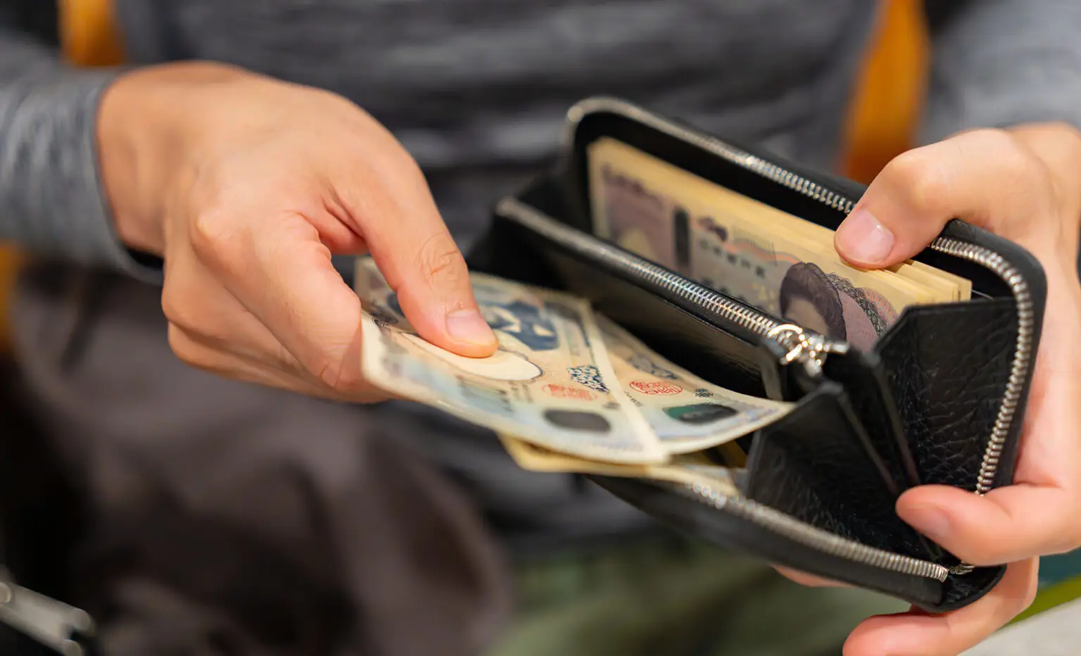 personne qui sort des billets d'un portefeuille pour payer lors d'un voyage au Japon