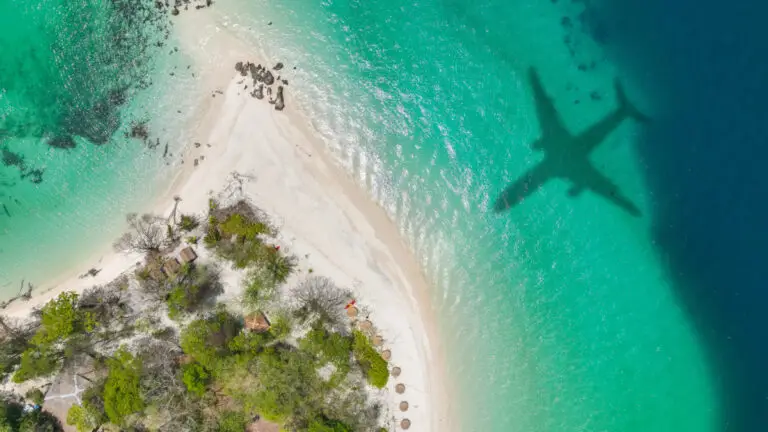 Avion qui survole une plage de sable blanc